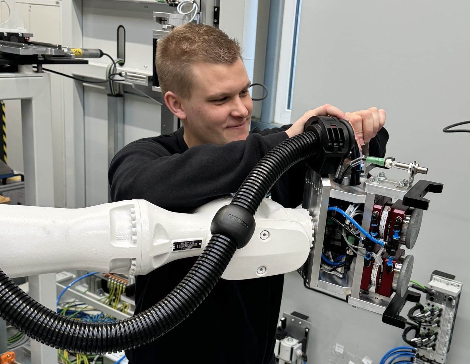 Eine Technikerin steht vor einem Schaltschrank und hält ein Steuergerät in der Hand.